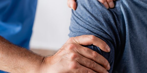 partial view of chiropractor working with injured african american man in clinic